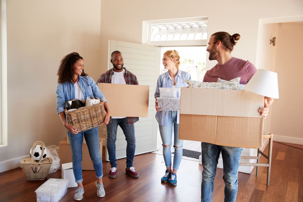 Group of friends helping to carry packed boxes for a move